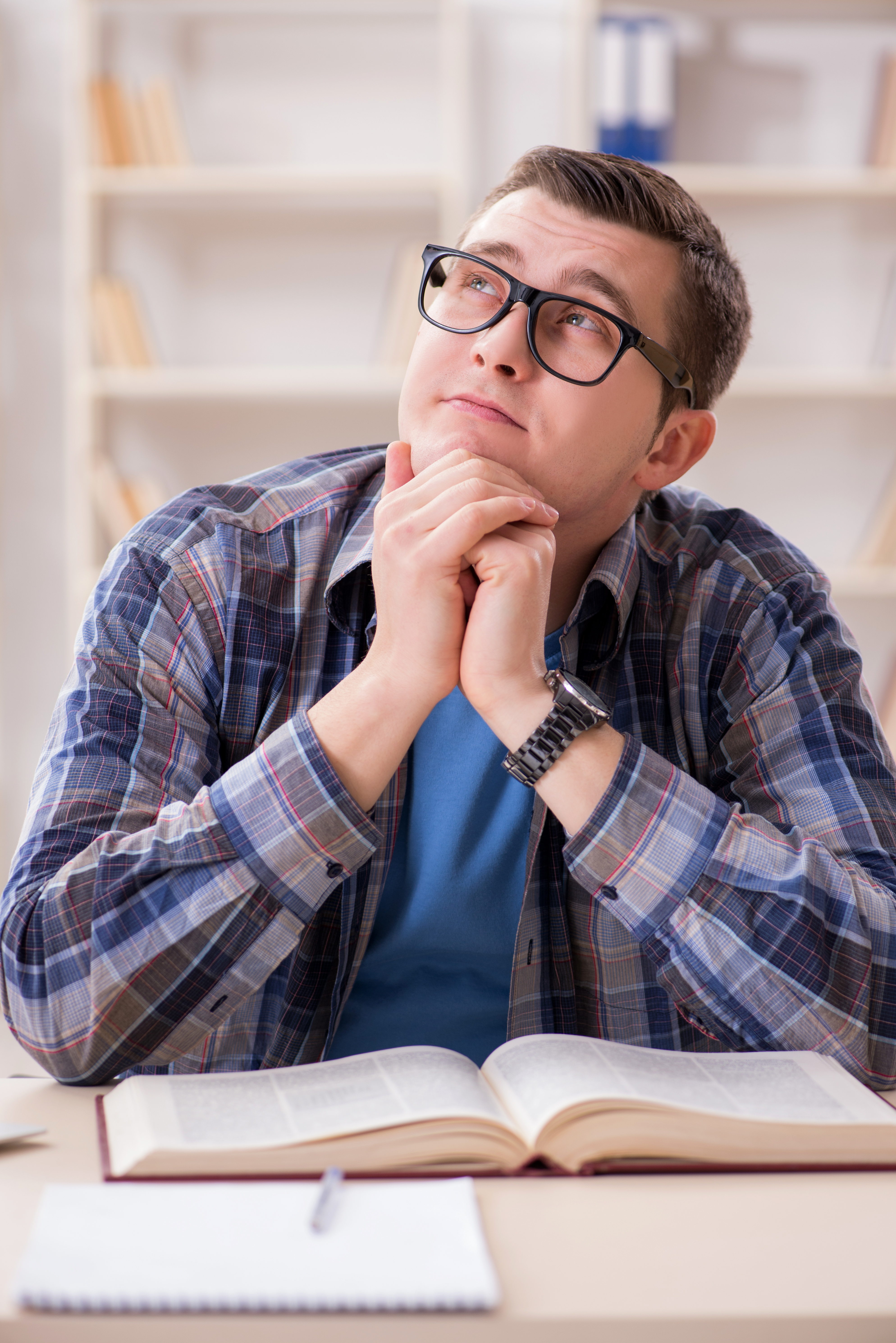Tænkende ung mand foran nogle bøger