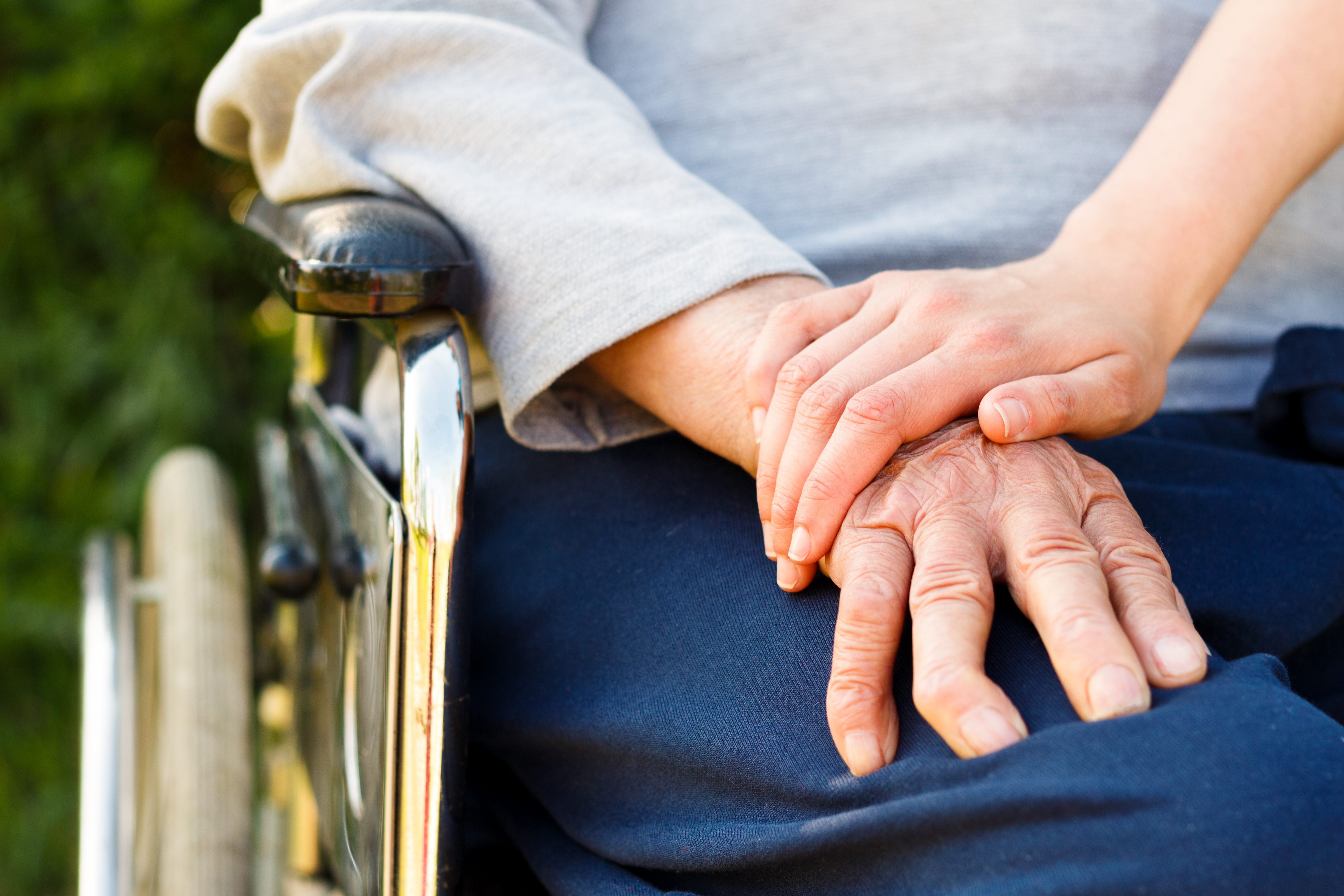 Kvinde der holder sin på en person i kørestol