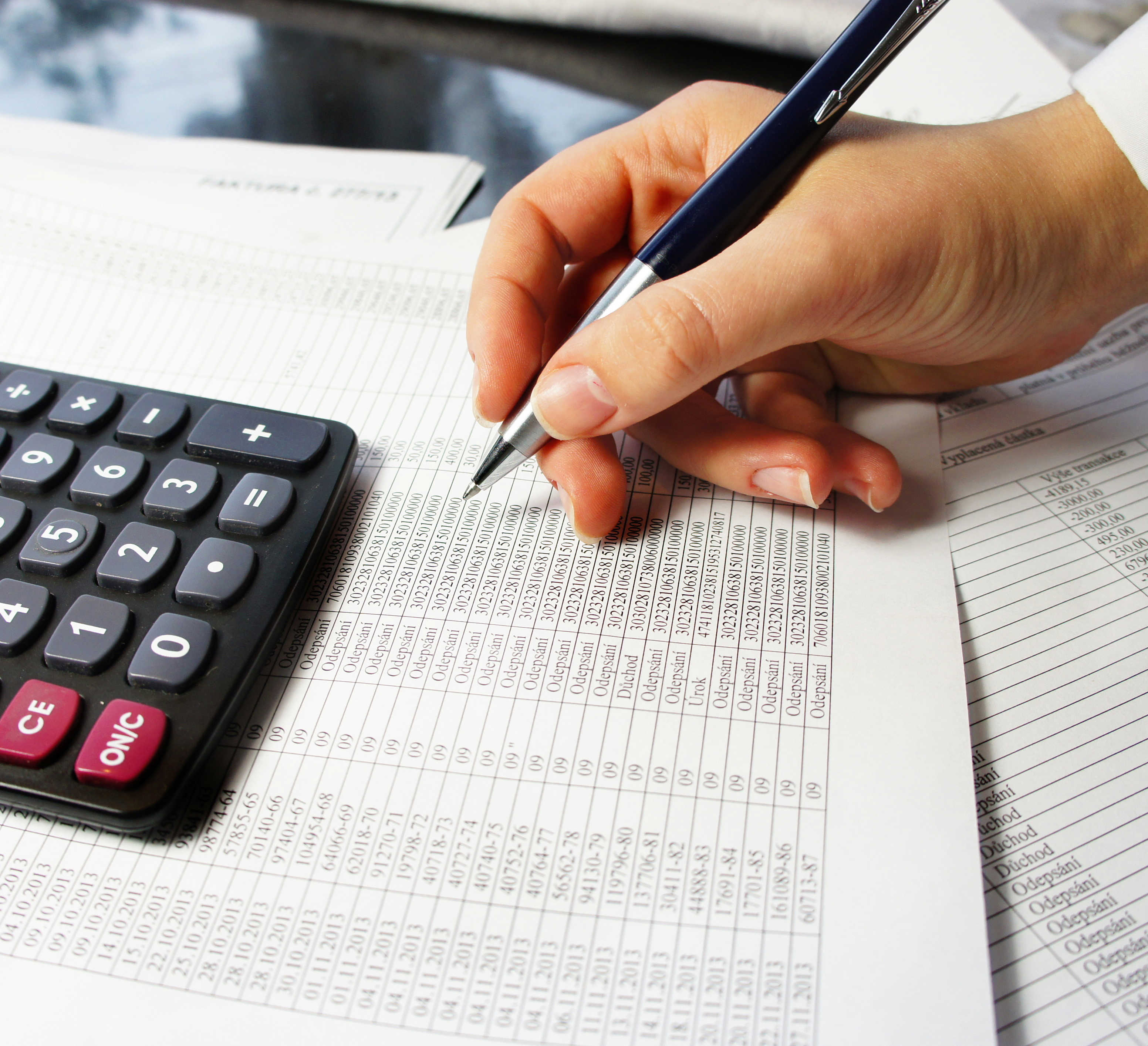 Hånd med kuglepen der laver regnskab