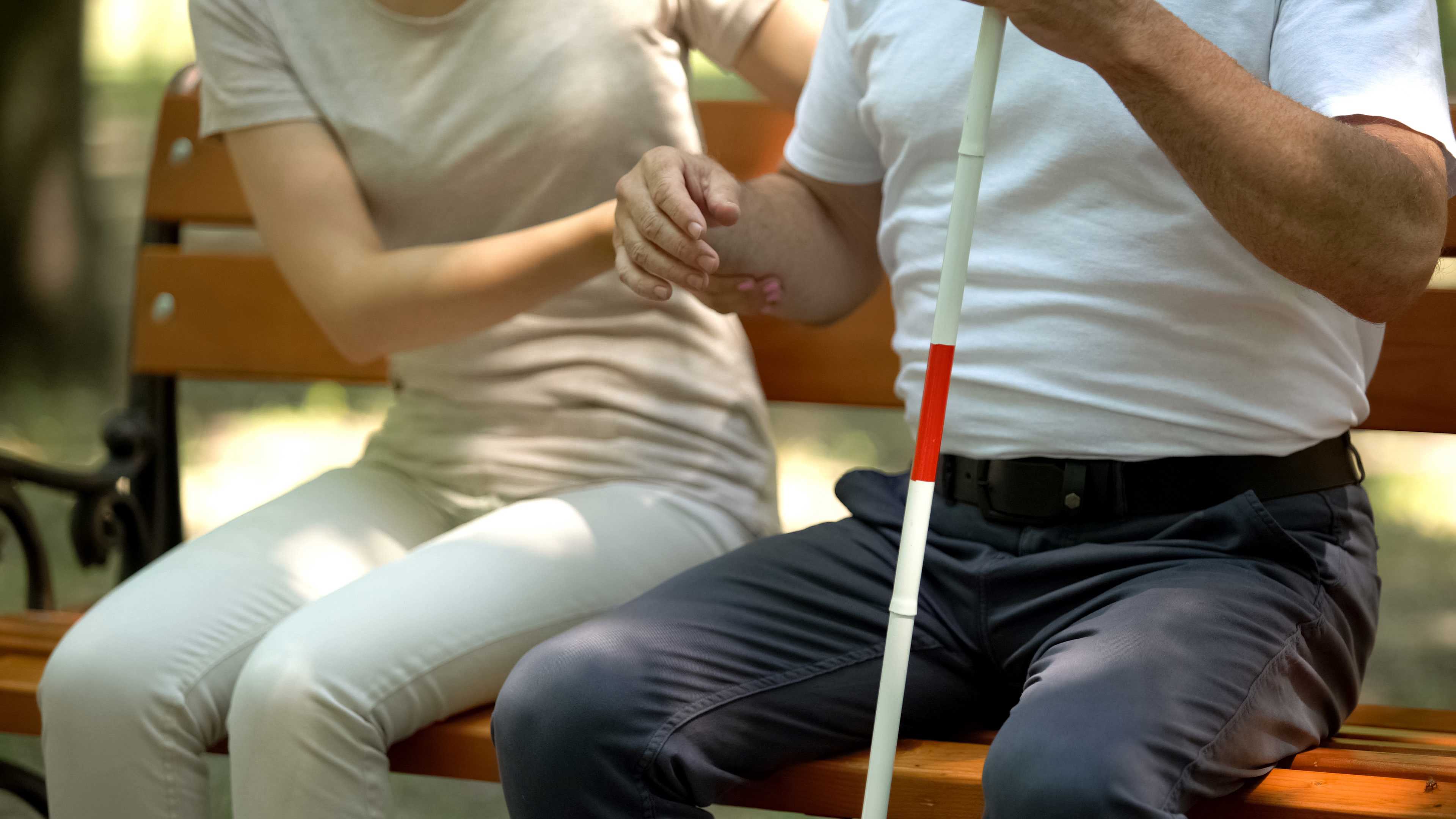 Kvinde støtter mand med blindestok