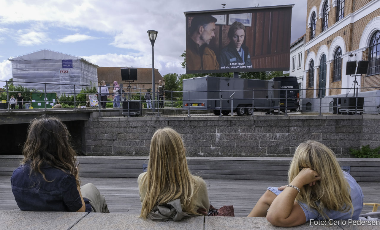 Unge mennesker ser kortfilm på amfiscenen ved Torvet