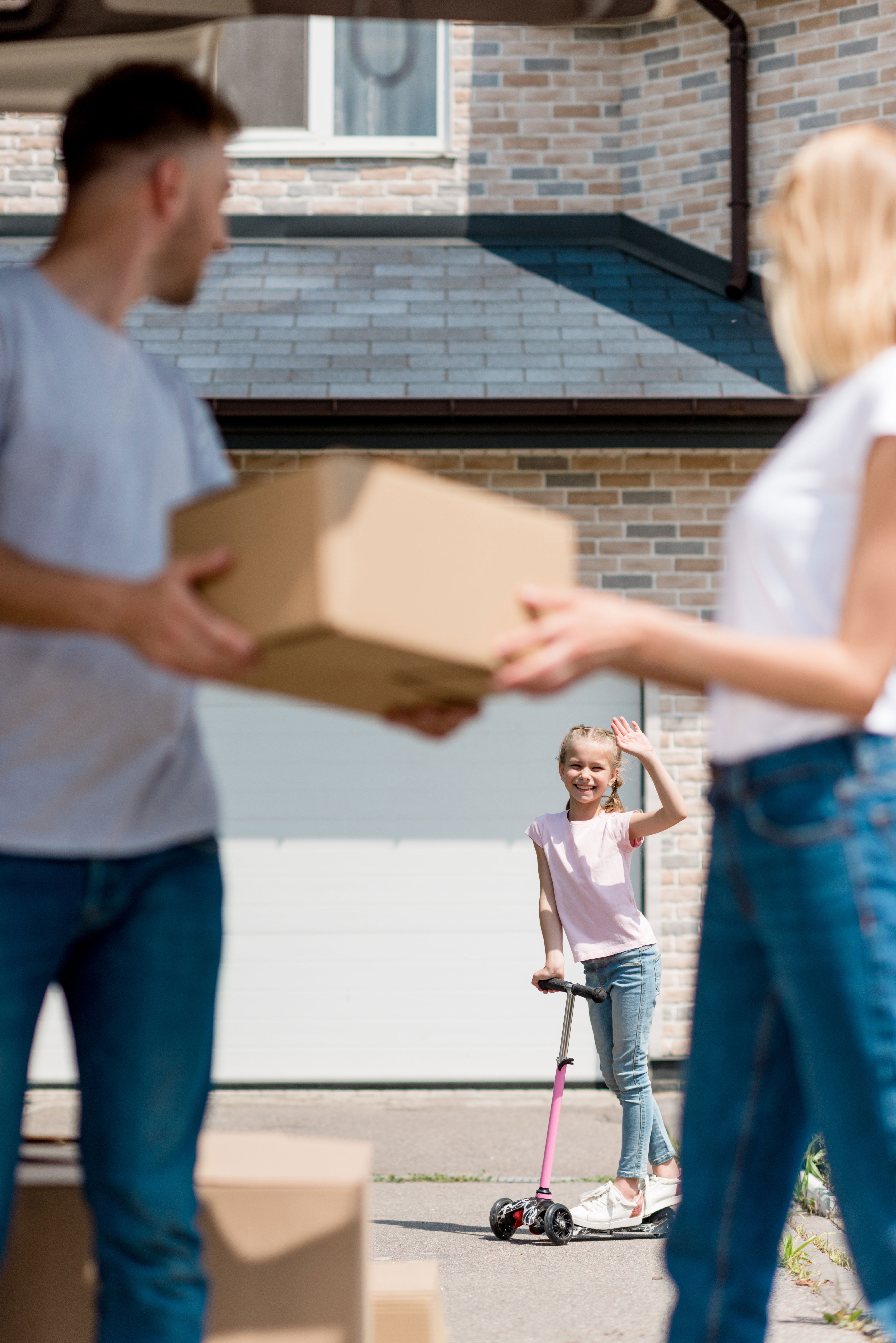 Forældre med en flyttekasse der kigger på deres datter i baggrunden