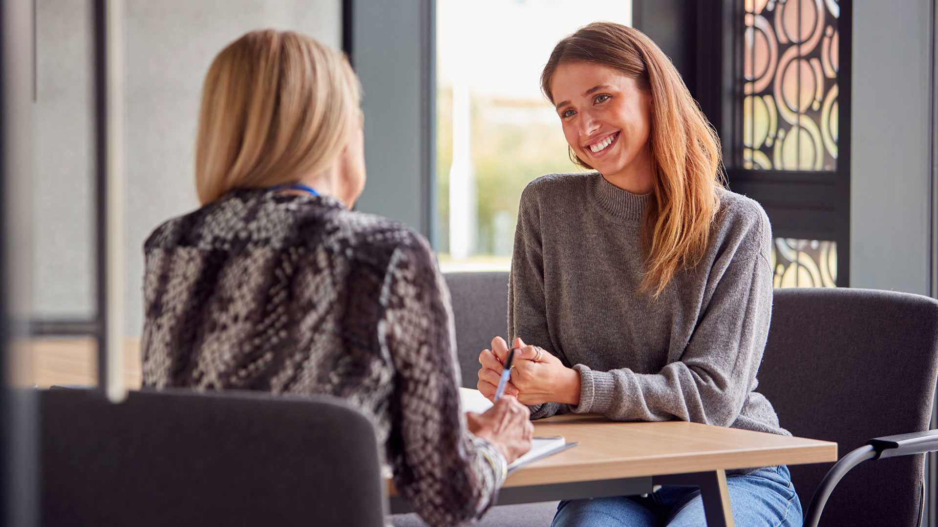 En kvinde modtager rådgivning af en anden kvinde med ryggen til