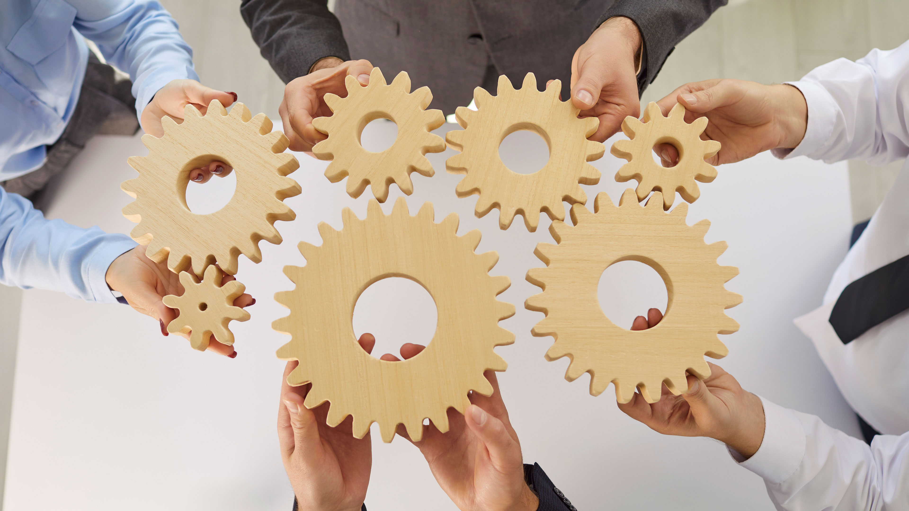 Hænder der holder tandhjul mod hinanden