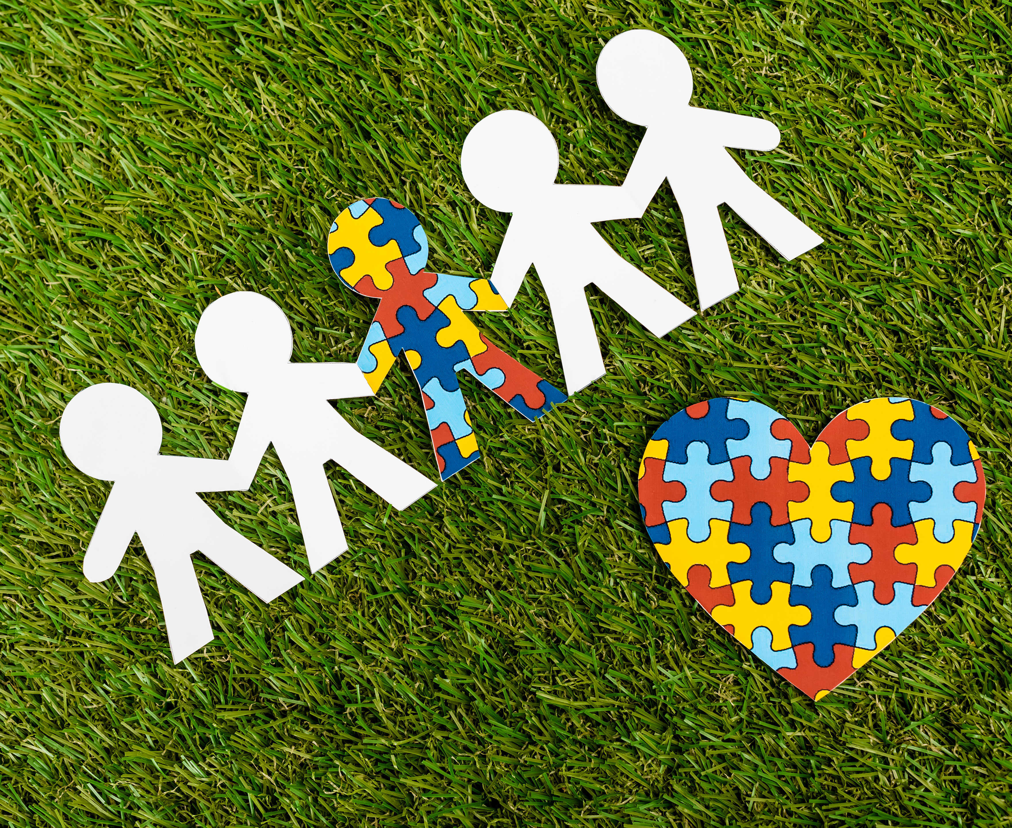 Hvide tændstikmænd på en græsplæne og en enkelt puslespilsbrik mand og et hjerte