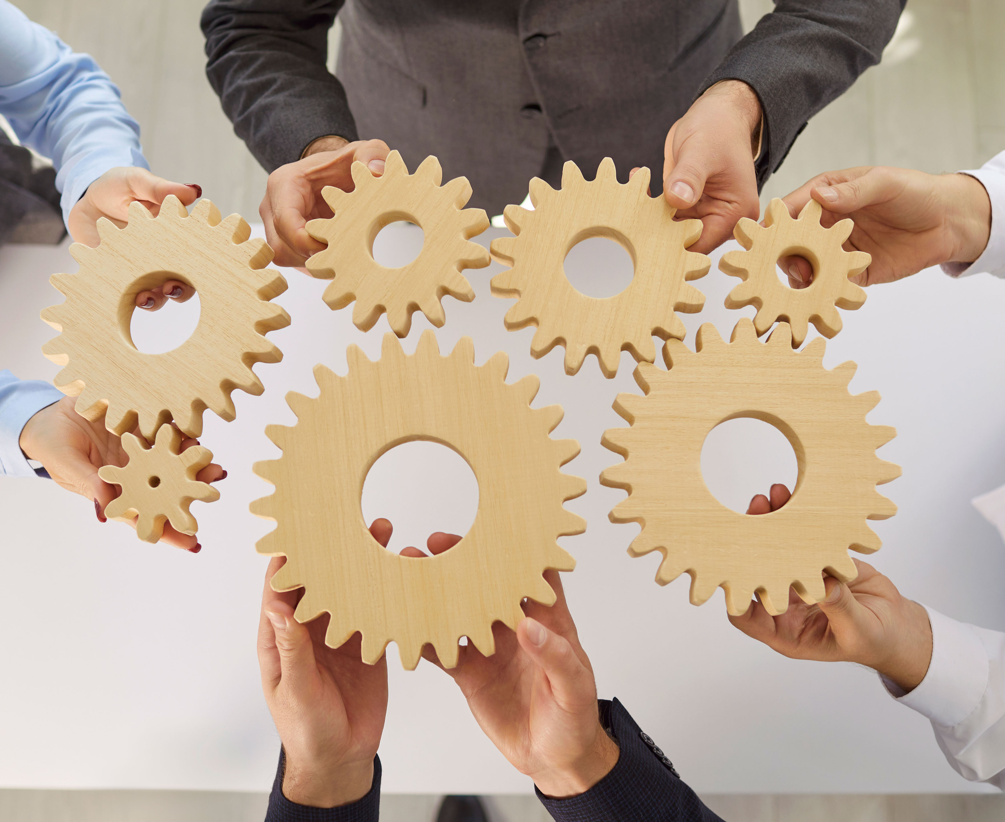 Hænder der holder en masse små tandhjul mod hinanden