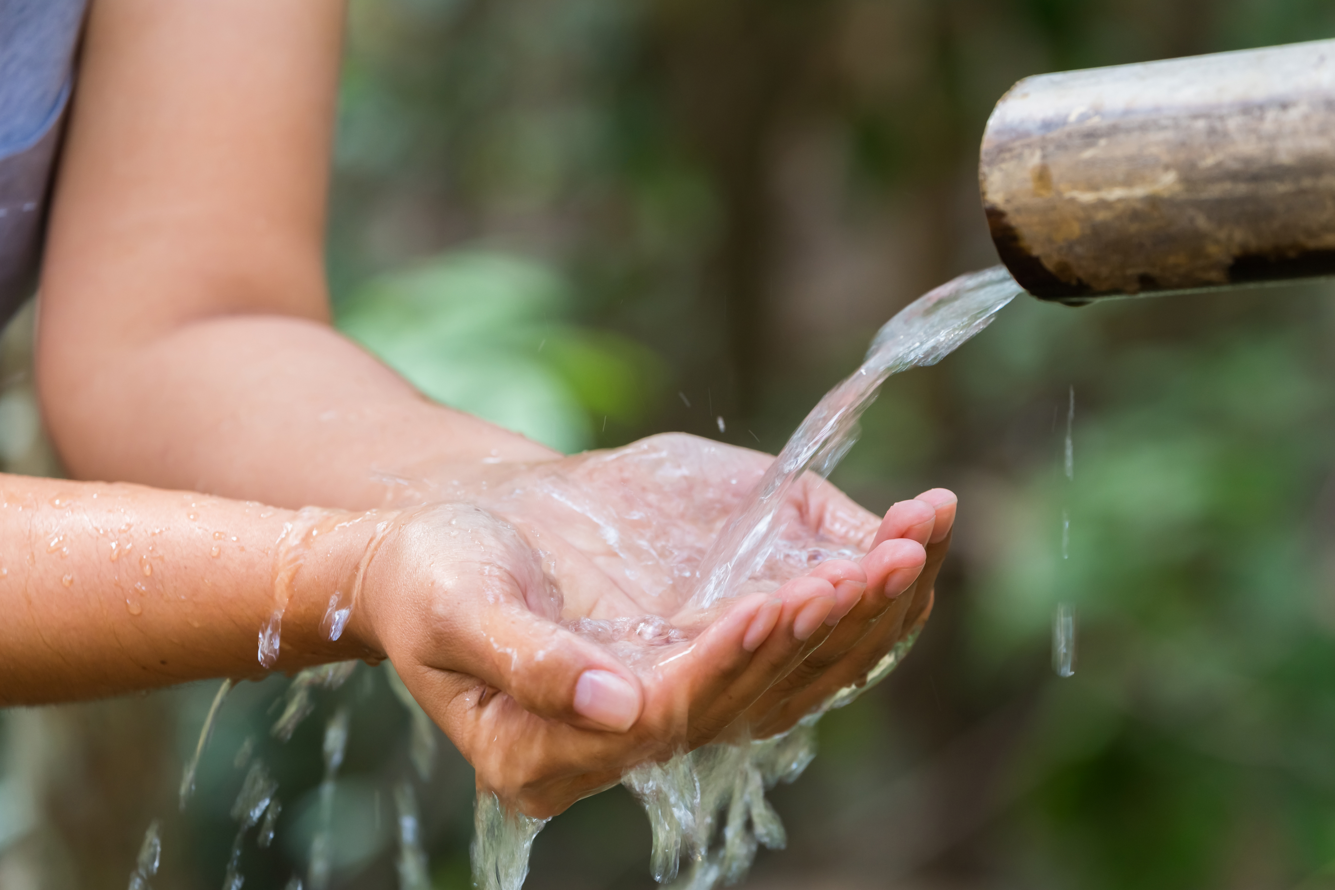 Hænder tager imod vand strømmende fra rør