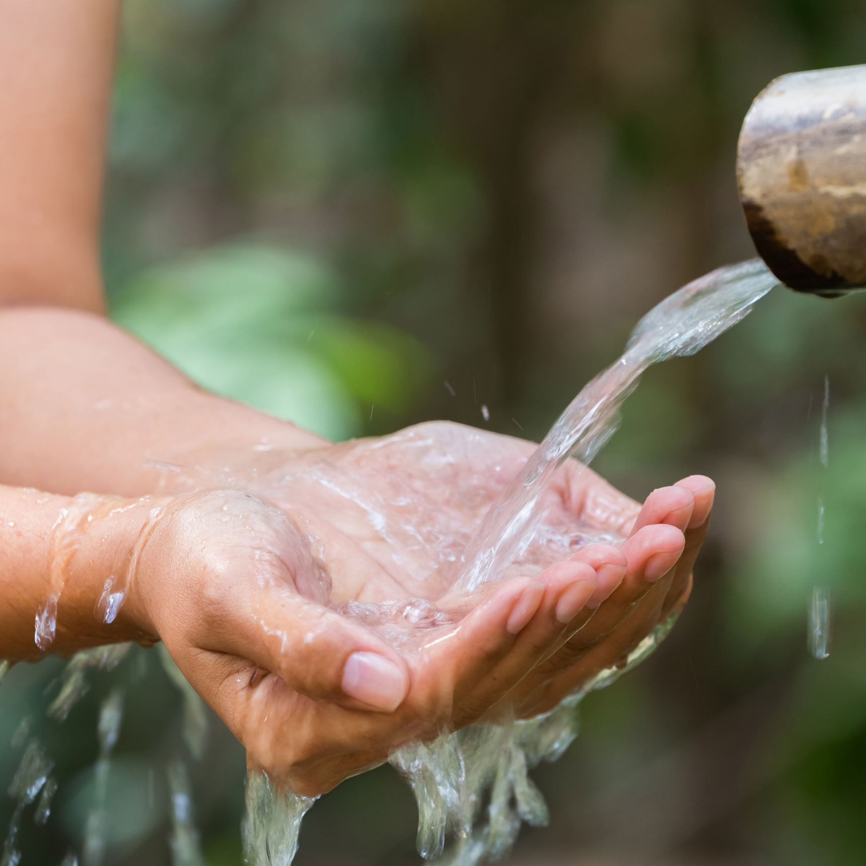 Hænder tager imod vand strømmende fra rør