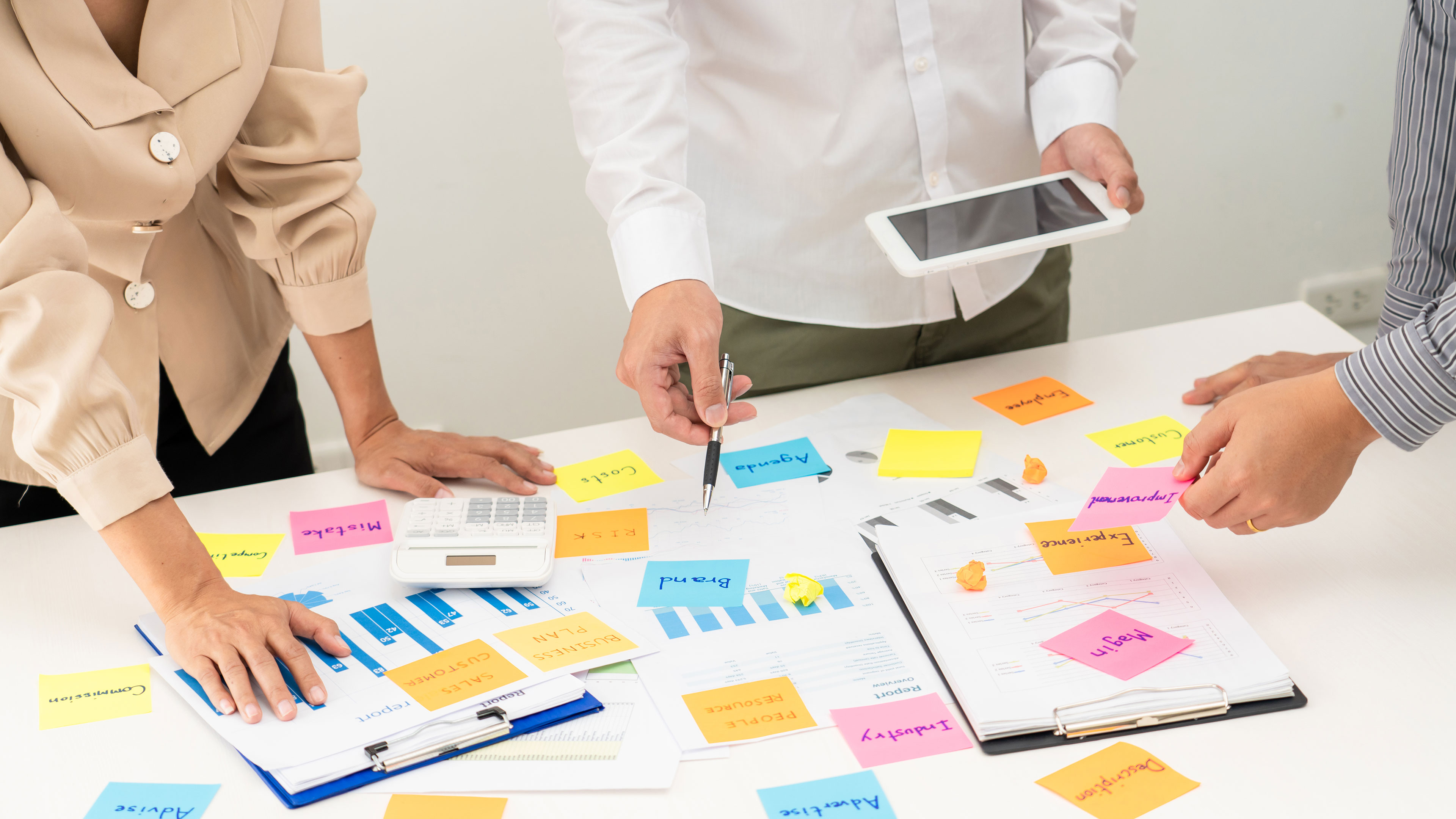 Folk stående over et skrivebord med masser af post-it sedler