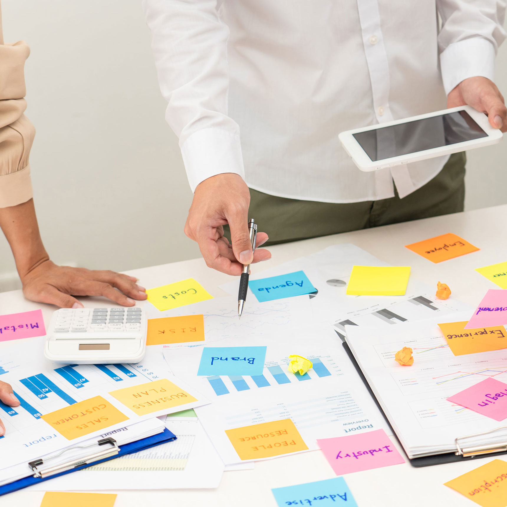 Folk stående over et skrivebord med masser af post-it sedler