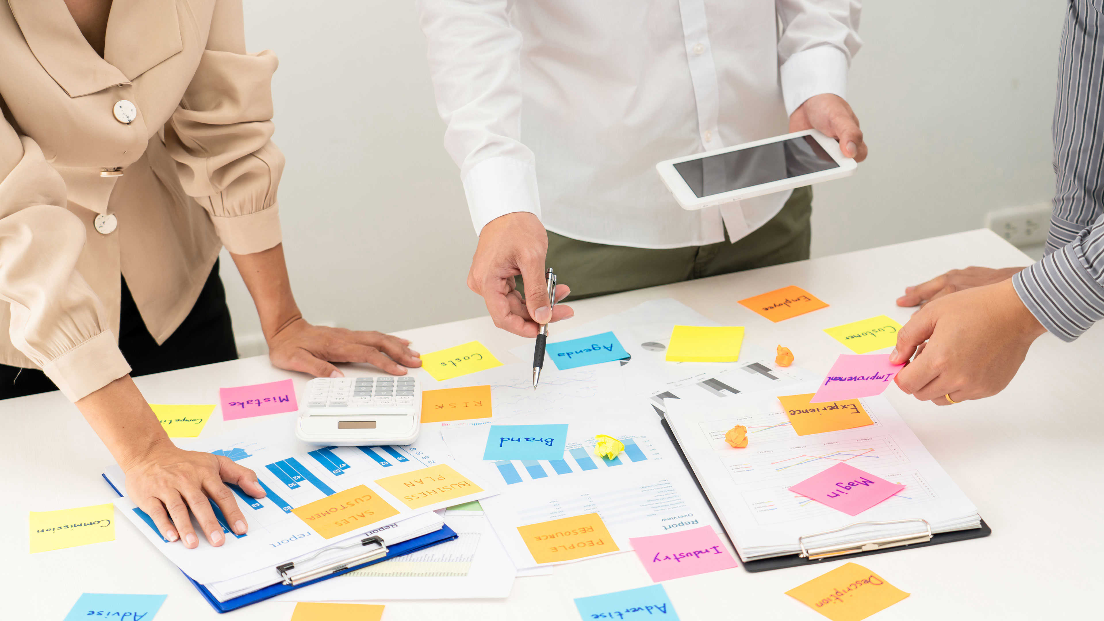 Folk stående over et skrivebord med masser af post-it sedler